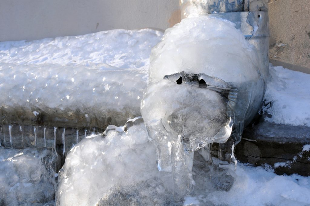 A heavily iced over frozen outdoor faucet to help illustrate why do pipes freeze?