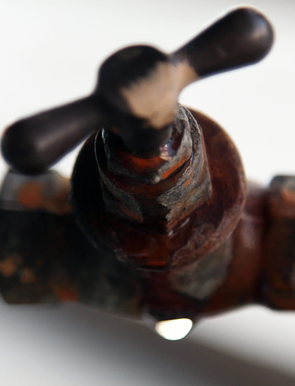 Rusty outdoor water pipe valve with a water drop to help illustrate outdoor plumbing Portland OR