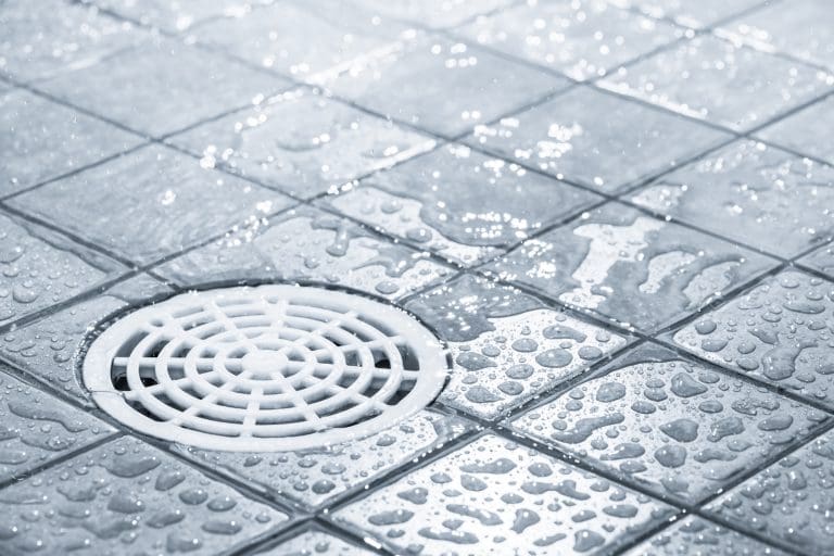 A shower drain set into a sloped tile floor to help illustrate floor slope requirements for a curbless shower