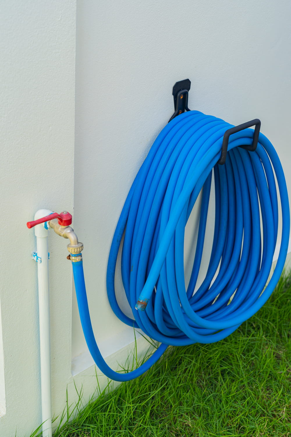 Faucet and blue hose for watering plants and lawns to help illustrate outdoor plumbing Portland OR