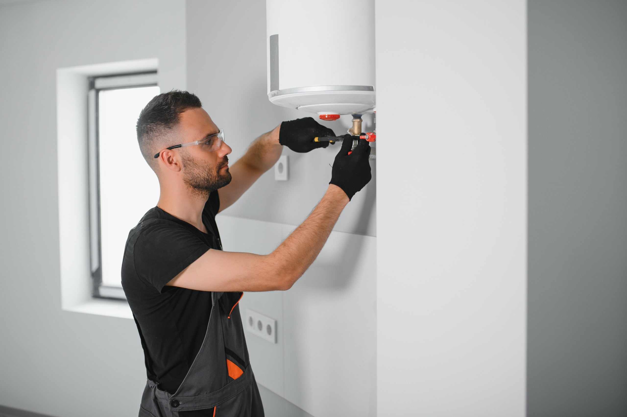 Professional plumber checking a boiler and pipes, boiler service concept.